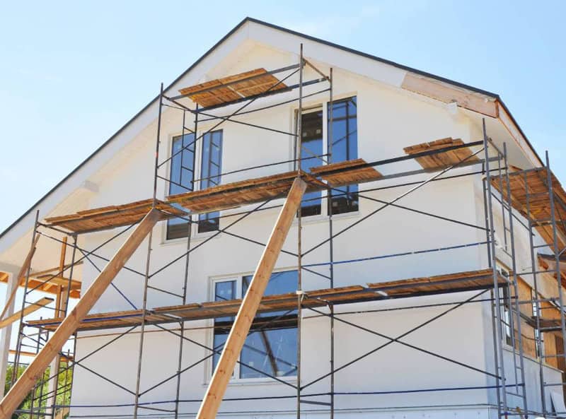 Maison blanche vu de profil avec un échafaudage devant.