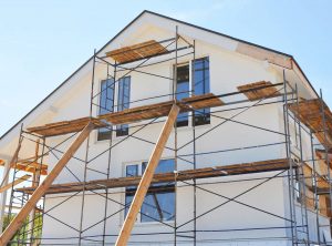 Façade après une rénovation Maison blanche vu de profil avec un échafaudage devant.