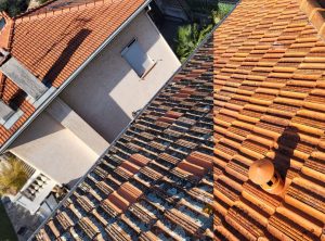 Toiture-pour-Home-page Une toiture en tuiles canal présente des signes de vieillissement. Les tuiles sont recouvertes de mousses, de lichens et de dépôts calcaires, notamment dans les zones ombragées.