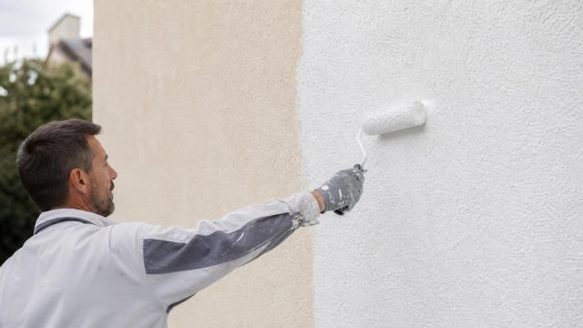 Application d’une sous-couche façade au rouleau sur un mur extérieur | Artihome Artisan appliquant une sous-couche façade au rouleau sur un mur extérieur avant peinture