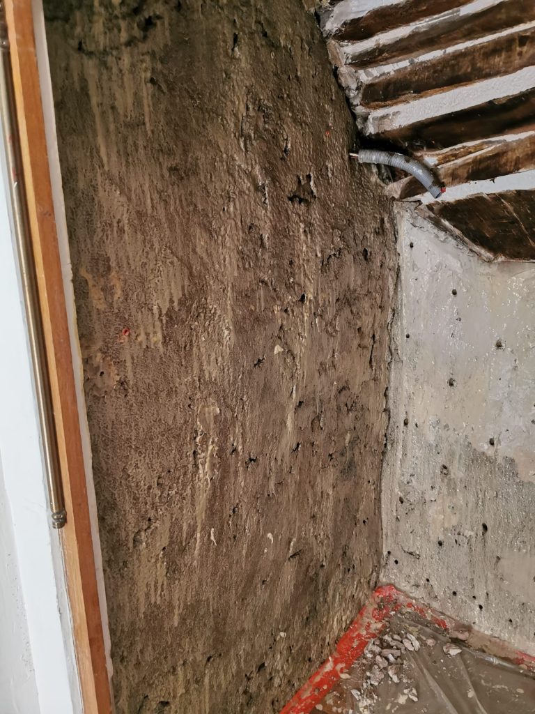 Mur en pierre à Jouques percé à sa base avant l’injection contre les remontées capillaires